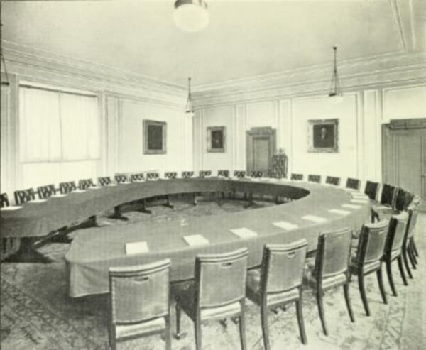 A photograph of a room containing a horseshoe-shaped table surrounded by chairs