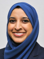 A headshot of Sana Luqmani smiling in front of a whiite background