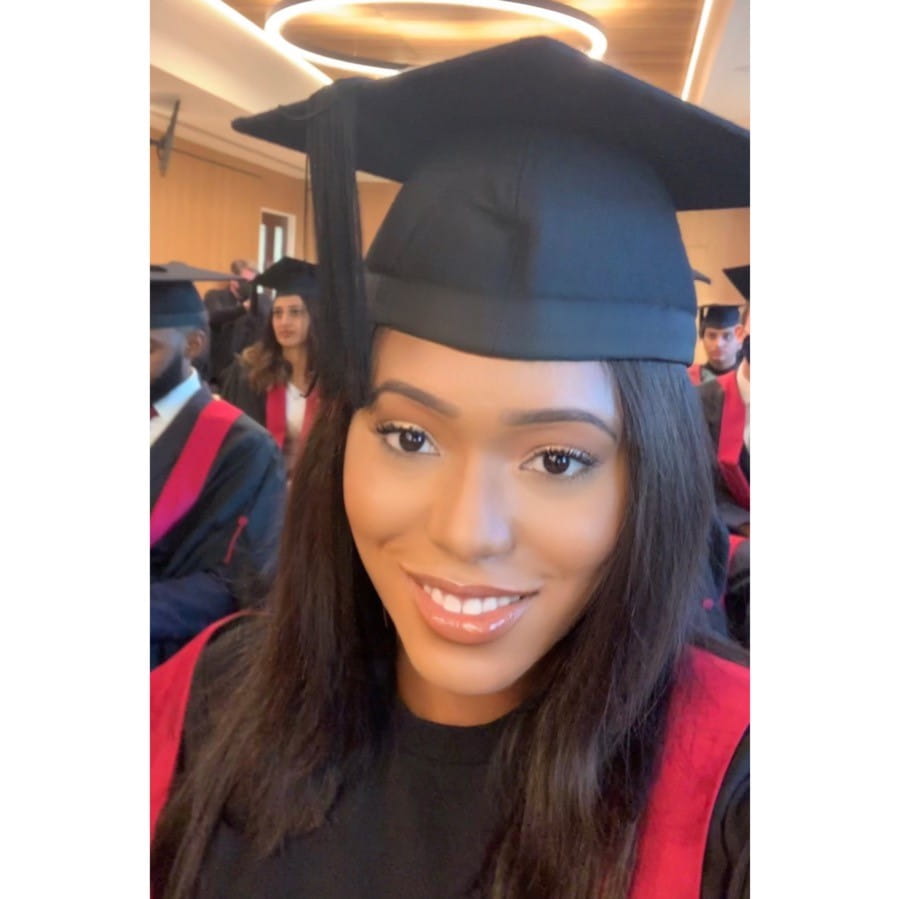 Sonia Eke sits smiling, in her graduation robes