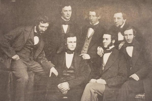 Sepia portrait of a group of 7 men in formal dress