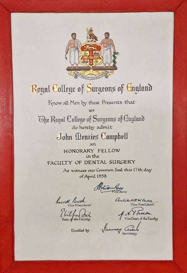 A red-framed certificate reading 'Royal College of Surgeons of England. Know all Men by these Presents that we The Royal College of Surgeons of England do hereby admit John Mernzies Campbell an Honorary Fellow in the Faculty of Dental Surgery. As witness our Common Seal this 17th day of April 1958.'